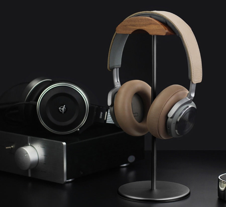Aluminum headphone stand holding headphones beside audio gear